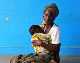 Woman breastfeeds her child while waiting for health services outside a health center in Nampula, Mozambique.