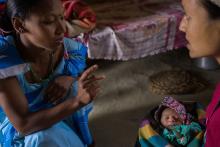 A woman is speaking to another woman holding a baby.