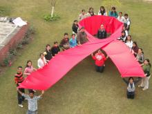 Source - © 2009 Gaurav Gaur, Courtesy of Photoshare. Description - Students of the Department of Social Work at Panjab University make a red ribbon to mark World AIDS Day in Chandigarh, India.