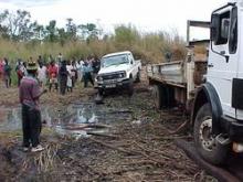 Residents gather as supply and service delivery trucks navigate a washed-out road in Ile district, Mozambique.
