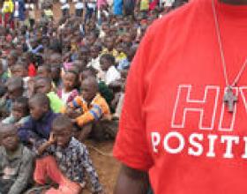 Close up of a man in a crowd wearing a "HIV Positive" t-shirt